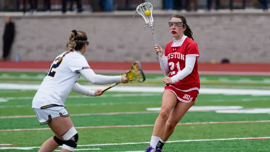 Photo of Jennifer Barry cradling the ball against a Merrimack defender.