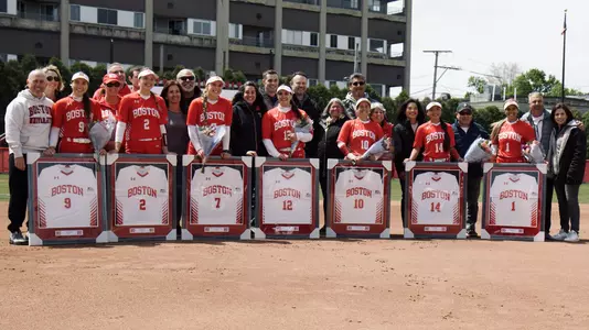 All seven BU softball seniors and their families pose for a group photo on the softball field.