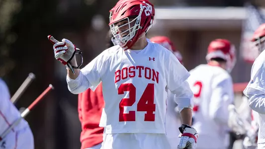 Mike DiIorio smiling and pointing while wearing his BU lacrosse uniform
