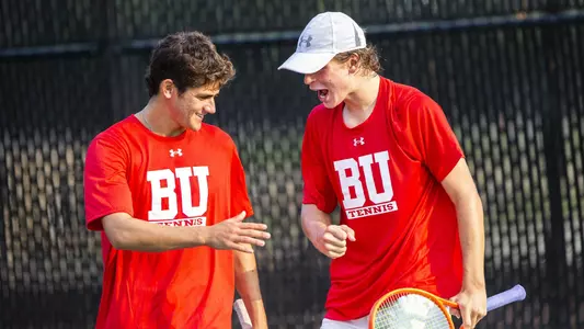 Men's Tennis doubles partners Jonah Dickson and Gabe Brown go to high five each other on the court.