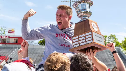 Jake Cates raises his arm in celebration as he holds the Patriot League championship trophy on the shoulders of his teammates