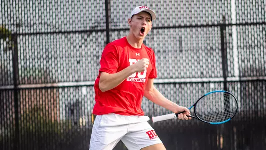 Cole Knutsen does a fist pump while jumping up off the court with a racquet in hand