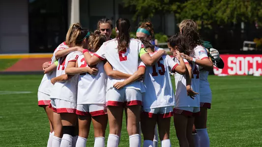 Photo of the women's soccer team huddling during a game against Michigan.