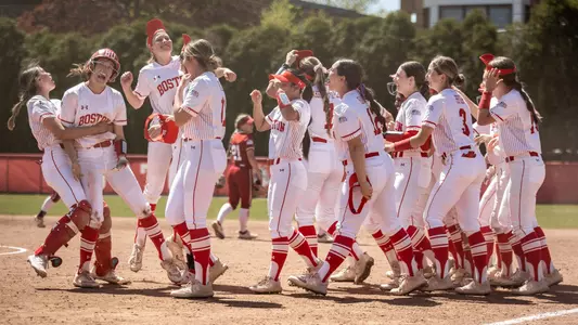 The BU softball team celebrates a walk-off win against Colgate by lifting each other up and shouting on the diamond.