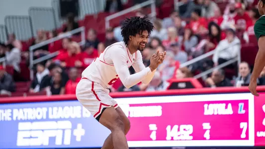 Miles Brewster claps his hands and smiling while getting into a defensive position near midcourt.