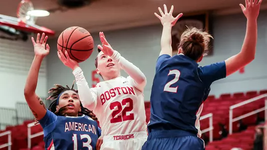 Photo of women's basketball senior Maggie Pina going for a floater near two American defenders.