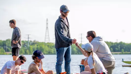 Photo of men's rowing assistant coach Alex Dillon fist-bumping a Terrier at the 2023 IRA Championships.