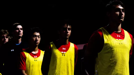 Men's soccer players wearing yellow bibs head onto the field.