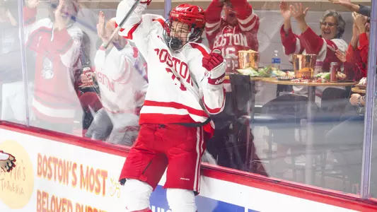 Macklin Celebrini leaps into the glass at Agganis Arena to celebrate his goal