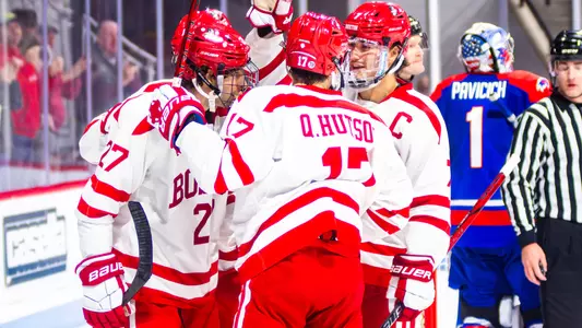 Men's ice hockey players celebrate a goal together
