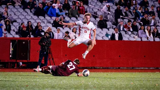 Andrew Rent flies over a Colgate player, who is sliding trying to kick the ball away.