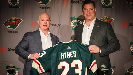 John Hynes and Bill Guerin holding a Minnesota Wild jersey with "Hynes 23" on the back