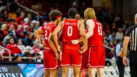 Five members of the BU men's basketball team huddle on the court at Davidson.