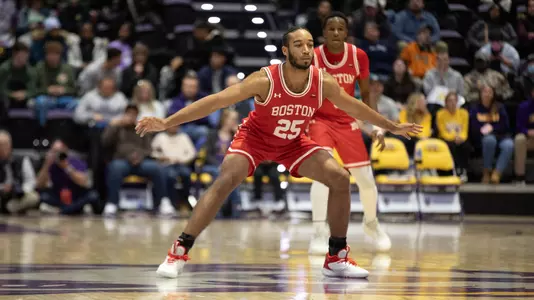 Spencer Joyner gets into a defensive position with arms spread out as Albany player brings the ball up the court.