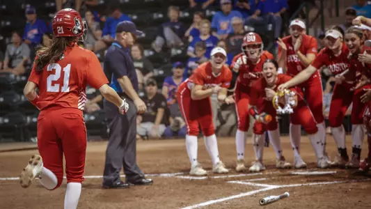 Kayla Roncin rounds the bases on a home run with her teammates celebrating behind home plate at South Florida