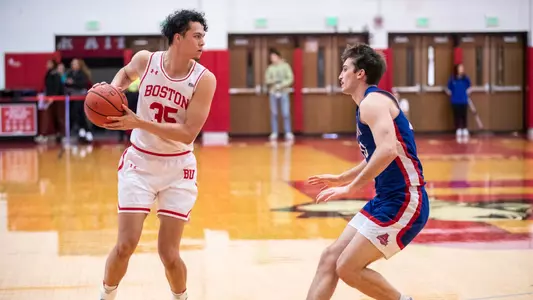 Fletcher Tynen holds the ball outside the arc looking to pass the ball with American defender close by.