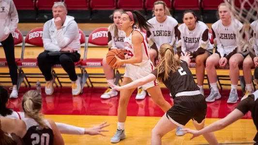 Photo of women's basketball senior Maggie Pina passing the ball in front of the Lehigh bench.