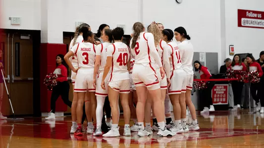Photo of the women's basketball team huddling before a game starts.