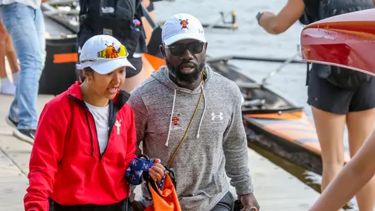 Photo of Lightweight Rowing Head Coach Malcolm Doldron talking to a student-athlete on the dock.