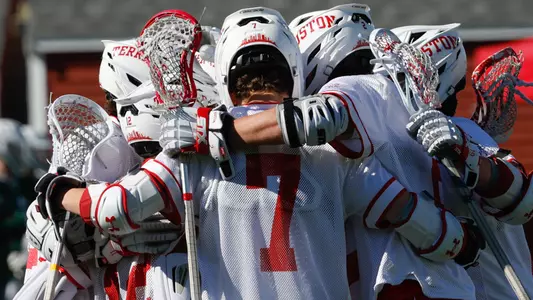 Men's lacrosse players huddling in celebration after scoring a goal
