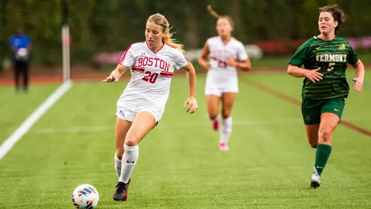 Photo of women's soccer sophomore Natalie Godoy dribbling the ball down the sideline while being chased by a Vermont player.