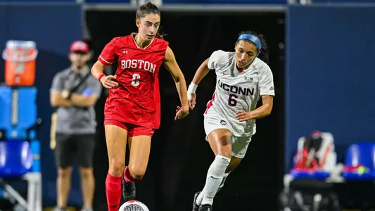 Photo of women's soccer freshman Samantha Aronson dribbling past a UConn defender.