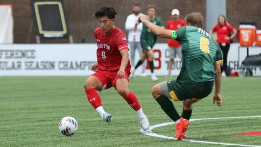 Daniel Kim dribbles the ball toward midfield with a Siena defender closeby.
