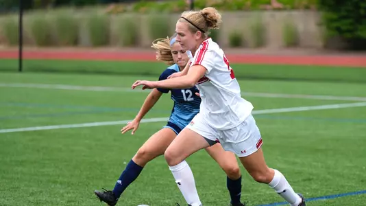 Photo of women's soccer junior Erin Sullenberger shaking off a Rhode Island defender.