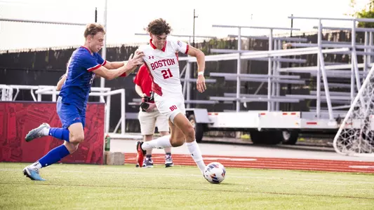 Eitan Rosen is dribbling the ball down the field with a UMass Lowell defender trying to grab a hold of him.