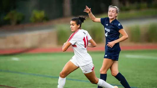 Photo of women's soccer sophomore Shayla Brown racing for a ball against a Maine marker.