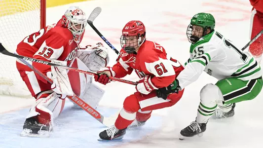 Alex Zetterberg skating in front of his own net next to a North Dakota player