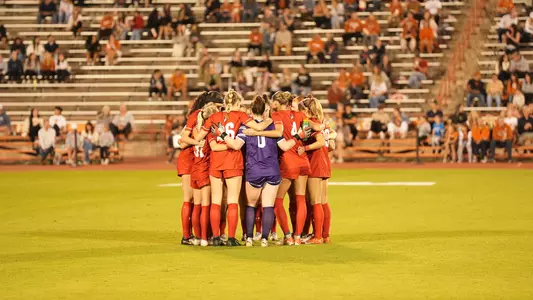 Photo of the BU women's soccer starters huddling up ahead of the match against No. 21 Texas in the 2024 NCAA Tournament.