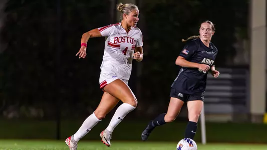 Photo of women's soccer junior Mackenzie Stickelman dribbling the ball as an Army defender approaches.