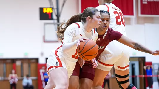 Photo of women's basketball sophomore Bella McLaughlin dribbling against a Rider defender.