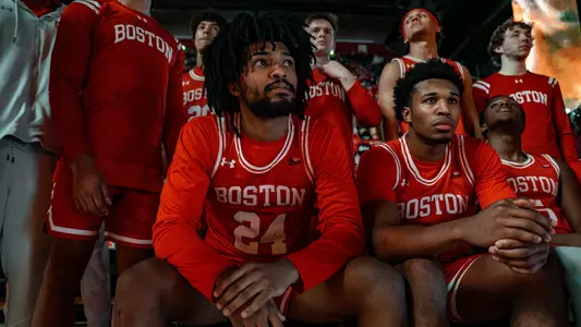 Men's basketball members are sitting on the bench waiting for their name to be called during starting lineup at Rutgers