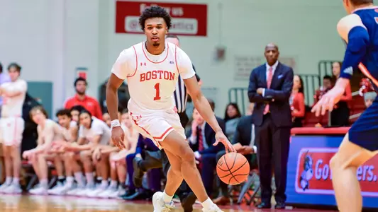 Ethan Okwuosa dribbles the ball up the court against Bucknell with head coach Joe Jones looking on from the bench standing