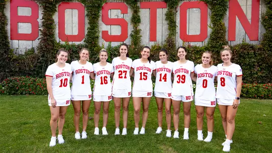 Women's Lacrosse Class of 2024 stands in front of the Ivy wall with Boston letters