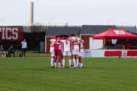 Men's soccer starters huddle on the field before the start of the first half.