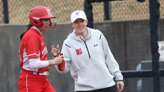 Boston University softball associate head coach Becca Carden is standing at first base next to senior Kayla Roncin.