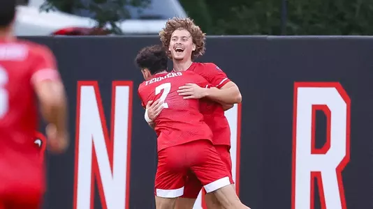 Quin DeLaMater jumps up in the air hugging a teammate after scoring a goal at Northeastern.