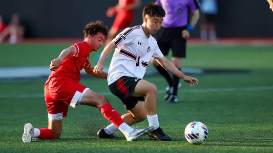 Jason Zacarias knocks a ball away from a Northeastern player with a sliding tackle.