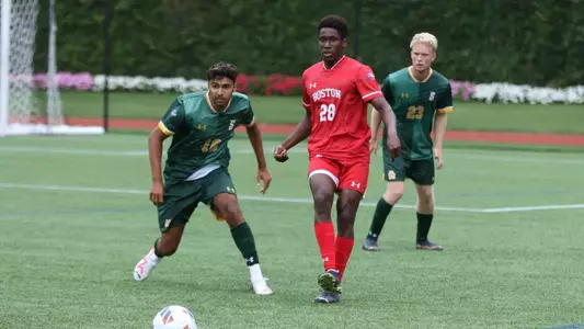 Keke Abai sends the ball up the field with two defenders around him trying to swipe the ball.