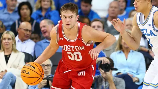 Ben Roy dribbles the ball up the court at UCLA with a defender close by.