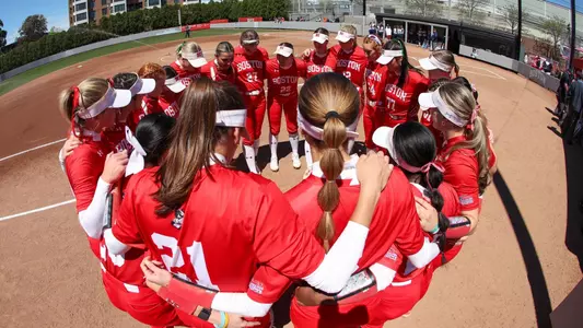 BU Softball team huddles in a circle before the start of a game.