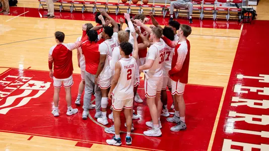Boston University men's basketball team huddle next to basket at Case Gym