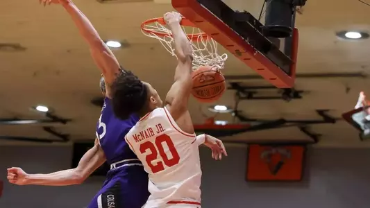 Michael McNair slams the ball through the hoop with a Holy Cross defender unsuccessfully trying to block the shot.