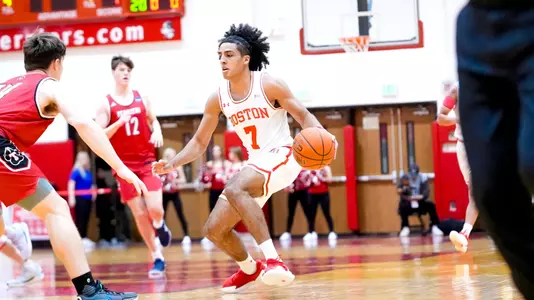 Azmar Abdullah dribbles the ball up the court while guarded by multiple Thomas College defenders.
