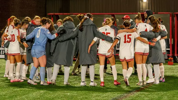 Photo of the BU women's soccer team huddling together after a win over Colgate.