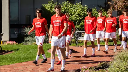Men's soccer team players walk out the Case Center door toward Nickerson Field