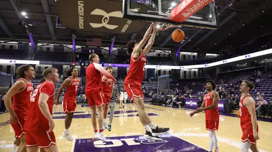 Chance Gladden hits a slam dunk with both hands with his teammates watching on during pregame warmup